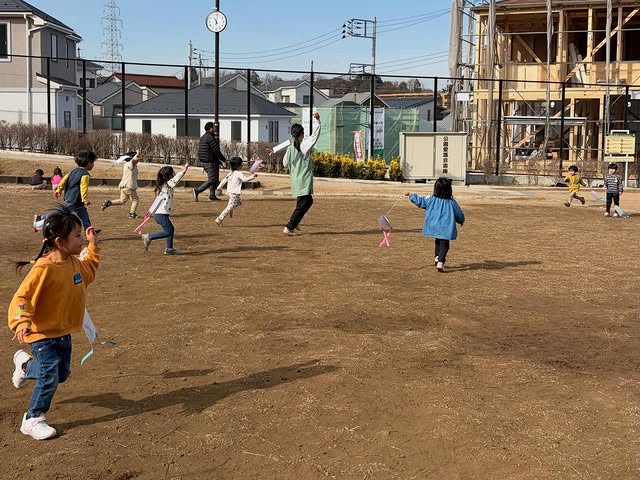 園庭で凧揚げをして走る子どもたち